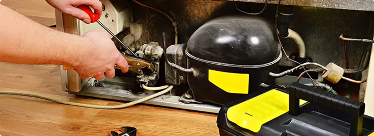 Refrigerator repair technician fixing the compressor and wiring in Costa Mesa, CA