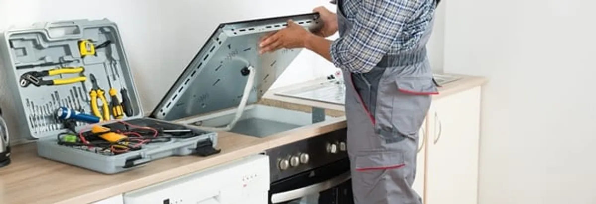 Cooktop repair technician lifting a built-in stovetop for service in Santa Ana, CA