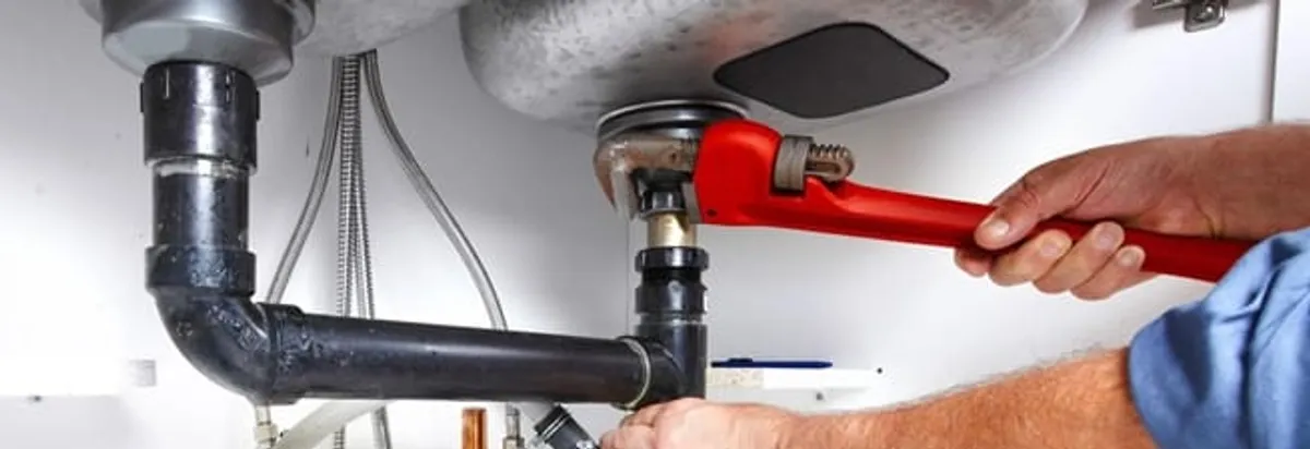 Garbage disposal repair technician tightening the sink drain and disposal connection in Santa Ana, CA