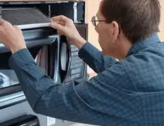 Appliance repair technician replacing a microwave vent filter in Santa Ana, CA