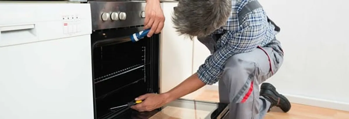 Oven repair technician inspecting and servicing an electric oven in Santa Ana, CA