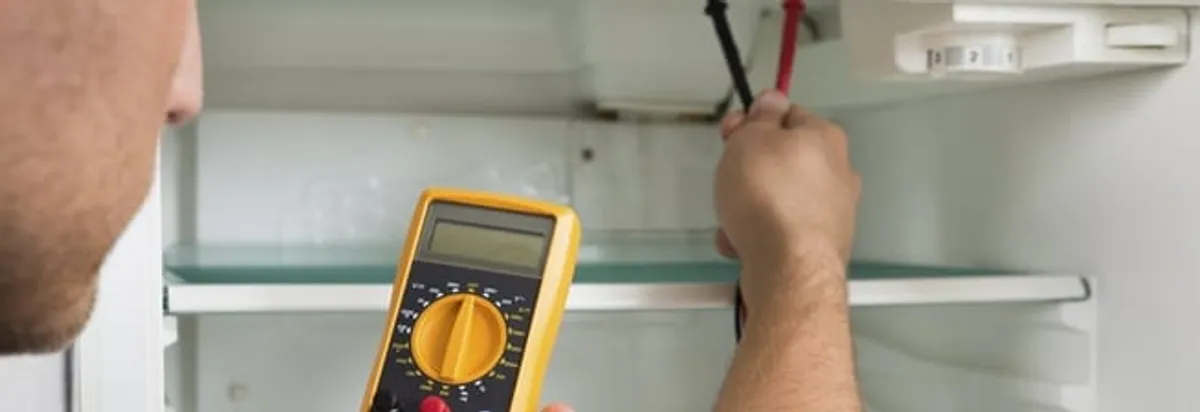 Refrigerator repair technician testing electrical components with a multimeter in Santa Ana, CA